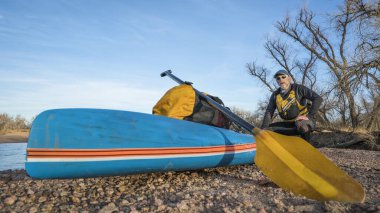 Kış boyunca çakıllı bir barda dinlenen yaşlı bir erkek kürekçi Kuzey Colorado 'daki Güney Platte Nehri' nde kürek çekiyor.