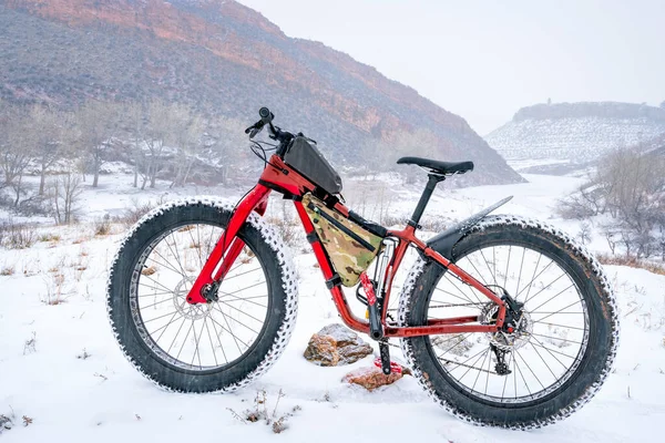 A fat mountaain bike in a snow blizzard at Colorado foothills at a shore of Horsetooth Reservoir  in Lory State Park, winter recreation and sport concept