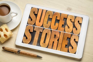 Başarı hikayeleri kavramı - bir fincan kahve ile dijital tablet üzerinde klasik harf baskı ahşap kelime soyut