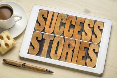 Başarı hikayeleri kavramı - bir fincan kahve ile dijital tablet üzerinde klasik harf baskı ahşap kelime soyut