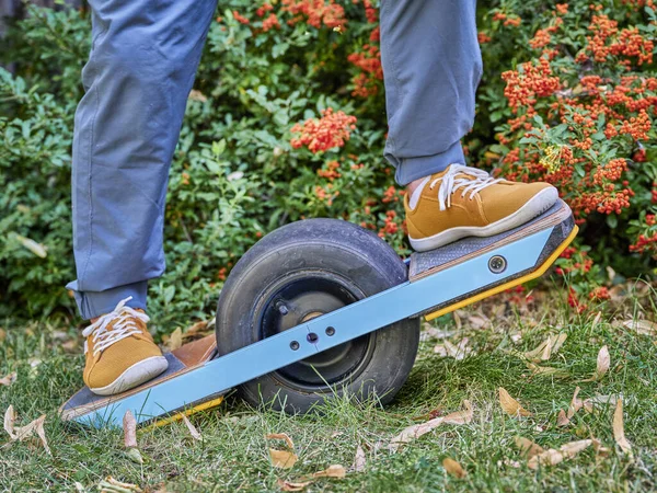 riding one-wheeled electric skateboard in a backyard or park