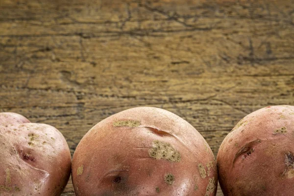 Batatas vermelhas em madeira rústica — Fotografia de Stock