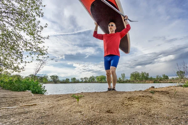 シニア卓球選手 paddleboard を運ぶ — ストック写真