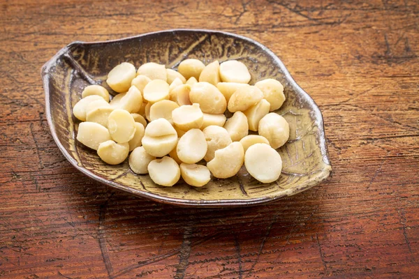 Nueces de macadamia en cuenco de hojas —  Fotos de Stock