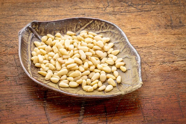 Bowl of pine nuts on rustic wood — Stock Photo, Image