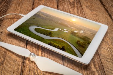Nebraska Sandhill 'den geçen bir nehrin üzerinde gün doğuyor. Dijital tablet üzerinde Orta Loup Nehri' nin hava görüntüsünü inceliyor.