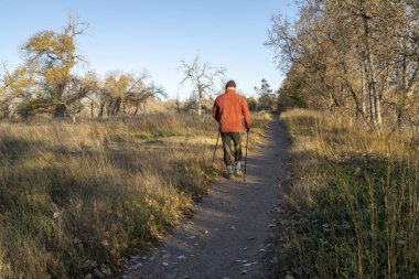 Üst düzey bir adam nehir kenarında bir patikada yürüyor.