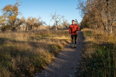 Üst düzey bir adam nehir kenarında bir patikada yürüyor.