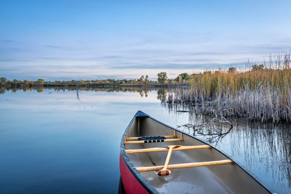 Crepúsculo sobre lago calmo com uma canoa — Fotografia de Stock