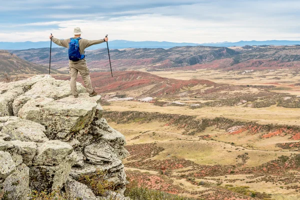 Hiker on rocky cliff overlooking valley — Stock Photo, Image