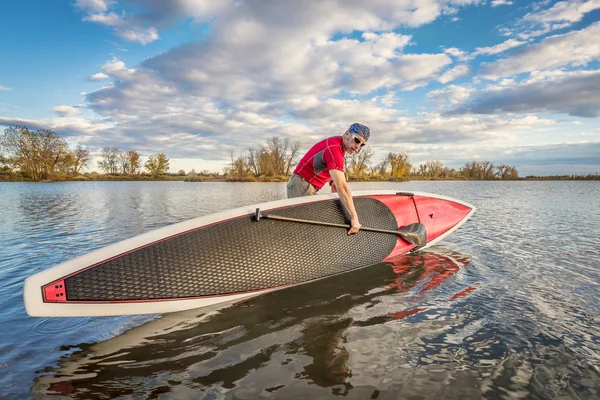Launching stand up paddleboard on lake — Stock Photo, Image