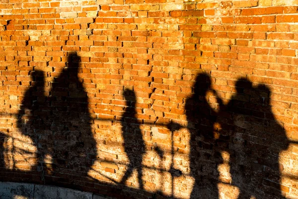 People walking, casting shadows on a wall — Stock Photo, Image