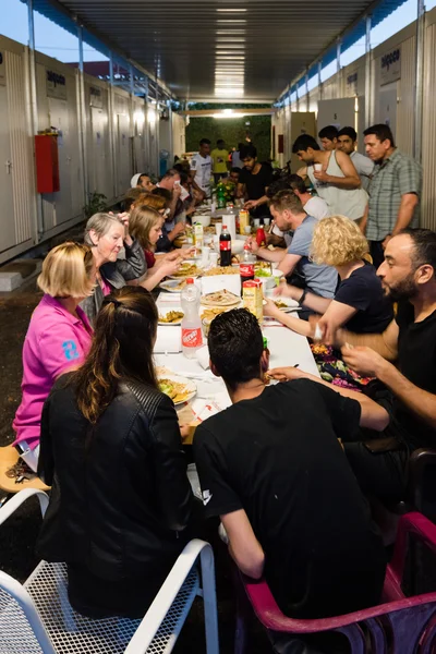 Refugiados muçulmanos e voluntários alemães se sentam juntos jantando durante o mês de jejum do Ramadã — Fotografia de Stock