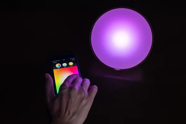 Kvinnlig hand använda Apple iphone för att styra en Philips Hue smarta hem ljus — Stockfoto