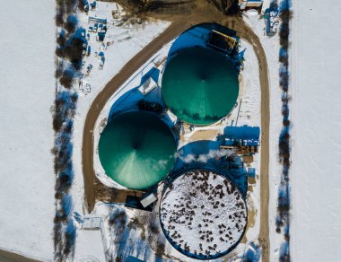 Açık bir kış gününde Güney Almanya 'daki biyokütleden yenilenebilir enerji üreten karlı tarlalardaki bir biyogaz fabrikasının hava görüntüsü