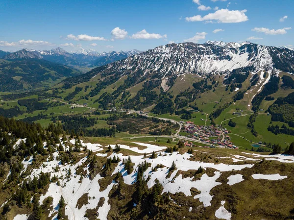 Mayıs ayının güneşli bir gününde Allgau Alpleri 'ndeki Oberjoch köyünün hava manzarası yüksek dağlardaki son karla birlikte — Stok fotoğraf