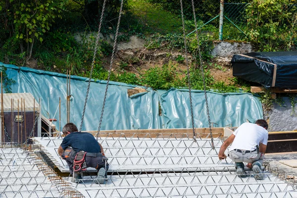 Kran hebt Teil eines Zementbodens mit Arbeitern, die sich anpassen — Stockfoto