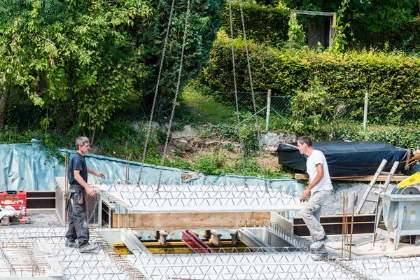 Kran hebt Teil eines Zementbodens mit Arbeitern, die sich anpassen — Stockfoto