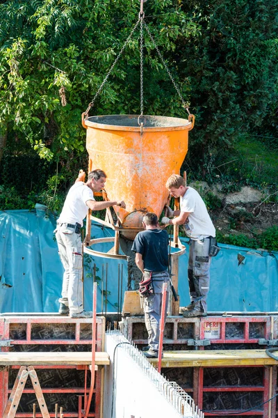 Trabajadores de la construcción en el sitio de construcción vertiendo hormigón en forma —  Fotos de Stock