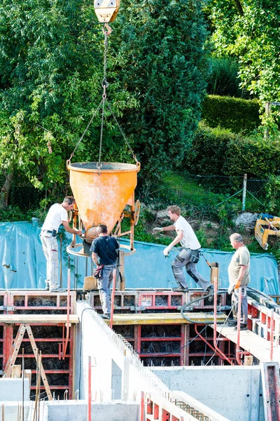 Trabajadores de la construcción en el sitio de construcción vertiendo hormigón en forma —  Fotos de Stock