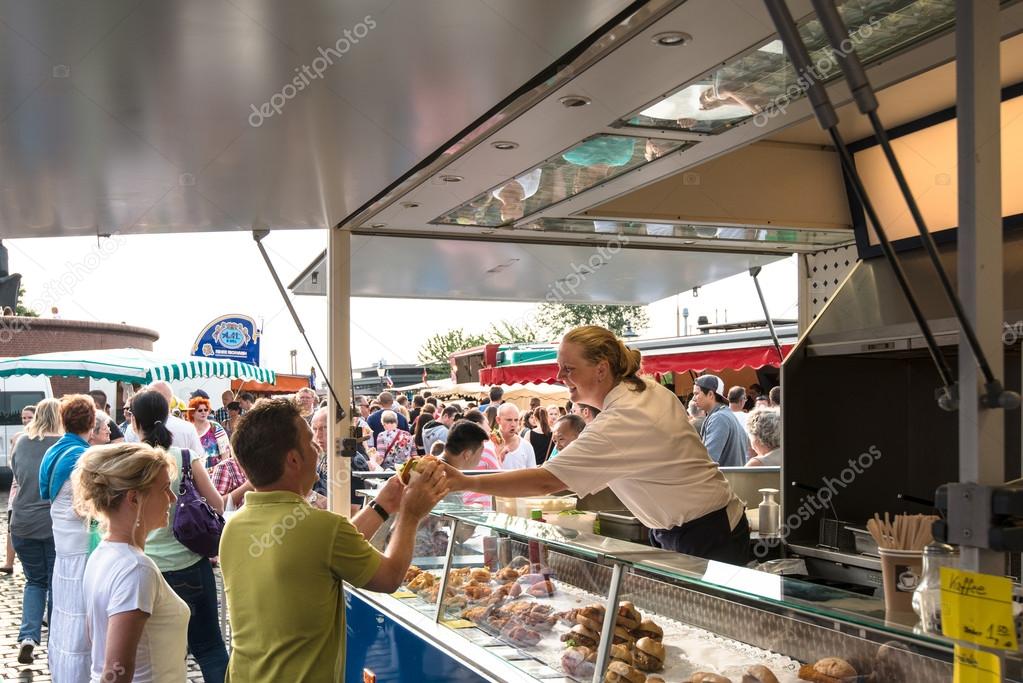 Hamburg, Germany - July 20, 2014: A fishmonger is selling a fish sandwich on the traditional Hamburg Fish Market  in the early Sunday Morning on July 20, 2014 in Hamburg, Germany. The Fish Market is active since the 16th century and traditionally ope