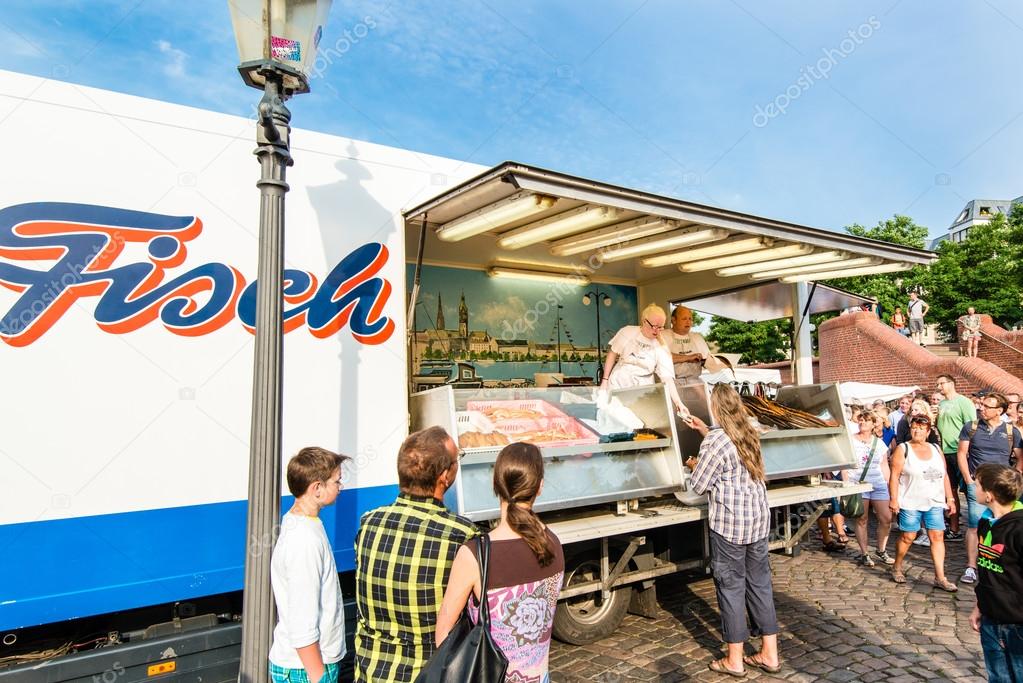 Hamburg, Germany - July 20, 2014: A fishmonger and his assistant are selling fish on the traditional Hamburg Fish Market  in the early Sunday Morning on July 20, 2014 in Hamburg, Germany. The Fish Market is active since the 16th century and tradition