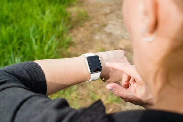 Mulher verificando seu Apple Watch enquanto caminha — Fotografia de Stock