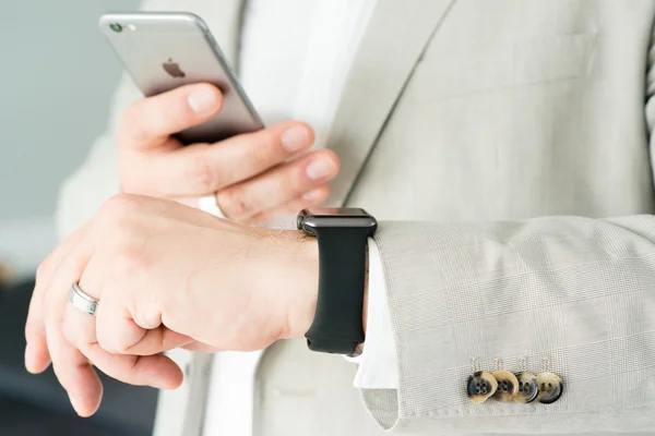 Empresário usando o Apple Watch e um Apple iPhone 6 — Fotografia de Stock