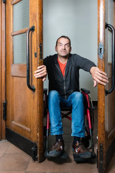 Man in wheelchair stuck between swing doors