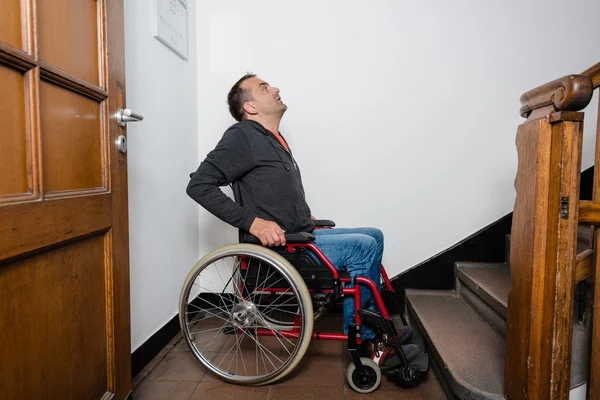 Homem em cadeira de rodas de frente para uma barreira de escadas — Fotografia de Stock