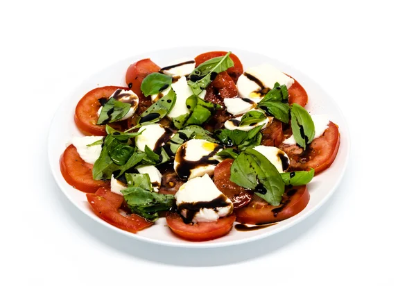 Tomato and mozzarella with basil leaves on a plate — Stock Photo, Image