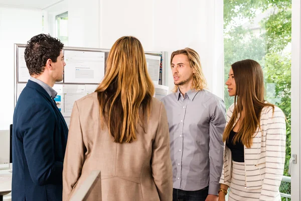 Businesspeople looking at bulletin board in office — Stock Photo, Image