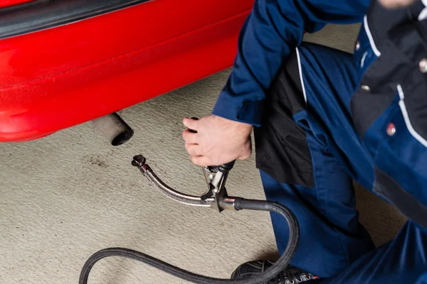 Mechanic measuring exhausts of a car in garage — Stock Photo, Image