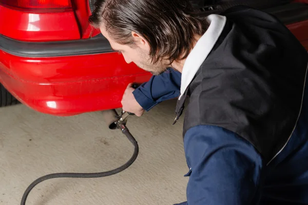 Mechanic measuring exhausts of a car in garage — Stock Photo, Image