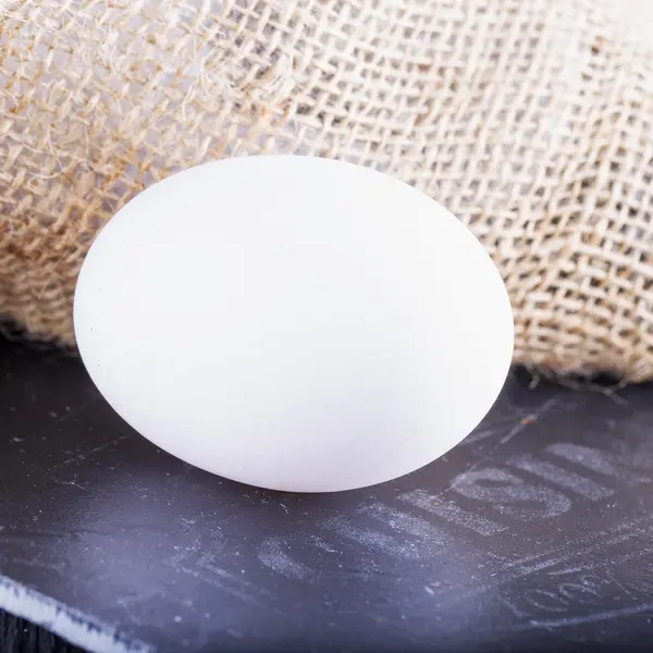 Ovo branco sobre pedra preta tábua de cortar — Fotografia de Stock