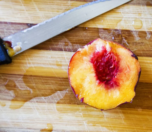 Нарізати персик над обрізною дошкою — стокове фото