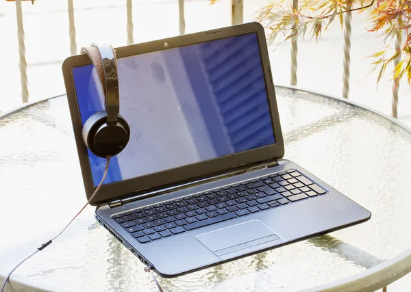 Laptop and headset over outdoor table — Stock Photo, Image