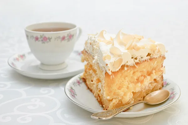 Piece of cake with white whipped cream and scattered almonds on