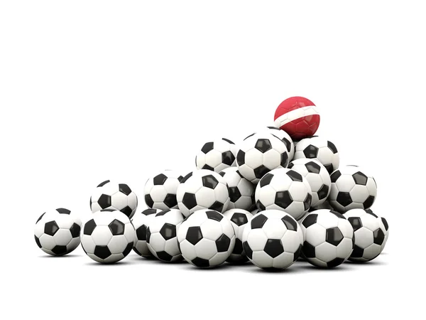 Högen av bollar fotboll med under lettisk flagg — Stockfoto