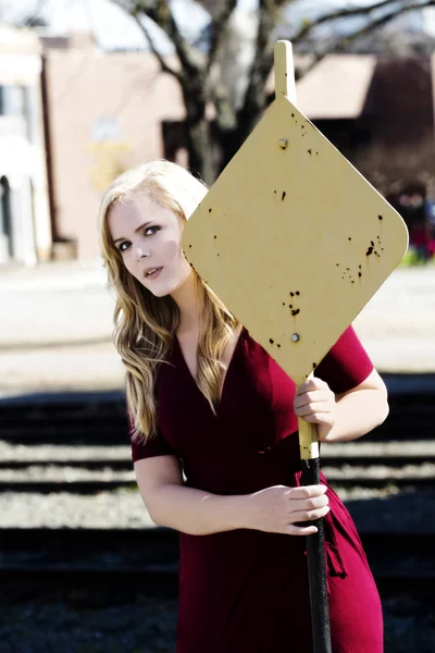 Blond Caucasian Woman In Red Dress Holding On To Yellow Sign — Stock Photo, Image