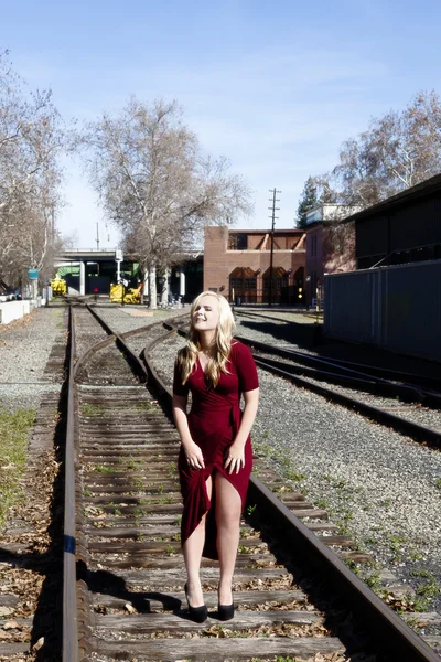 Loira mulher de pé na estrada ferroviária faixas vestido vermelho — Fotografia de Stock