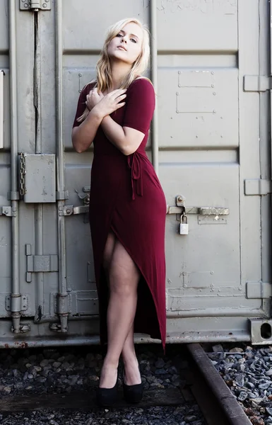 Mujer rubia de pie vestido rojo al aire libre contenedor de metal — Foto de Stock