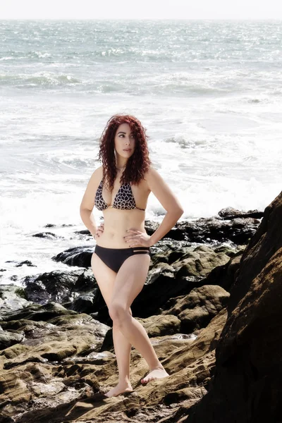 Latina mujer de pie sobre rocas en bikini con océano — Foto de Stock