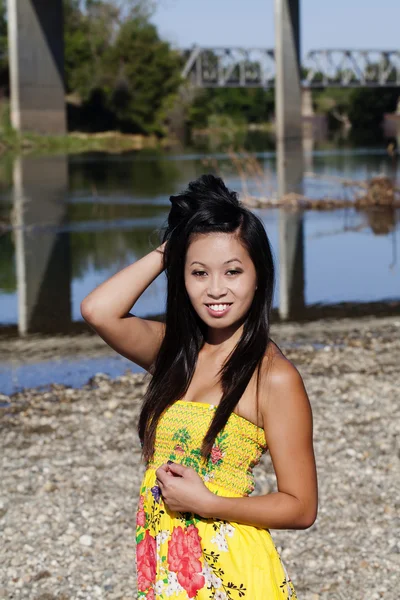 Ásia americano mulher amarelo vestido rio sorrindo — Fotografia de Stock