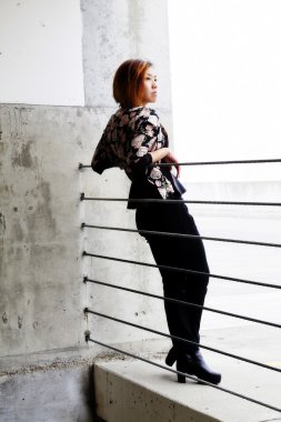 Asya Amerikalı kadın kabloları beton duvara yaslanmış