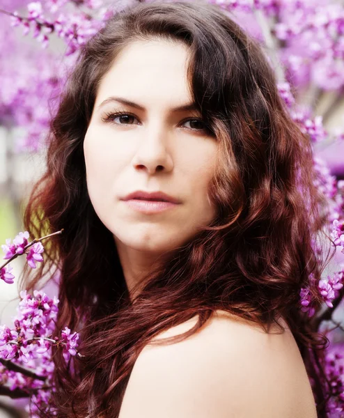 Kaukasische vrouw portret onder rode Bud Blossoms — Stockfoto