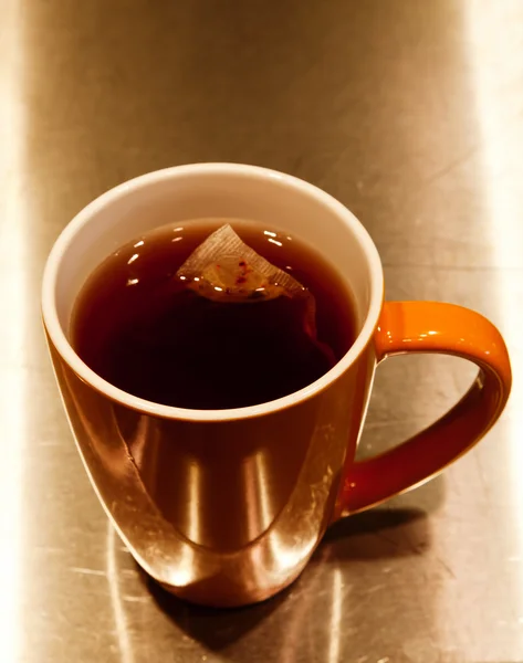 Sachet de thé trempant dans une tasse en céramique orange — Photo