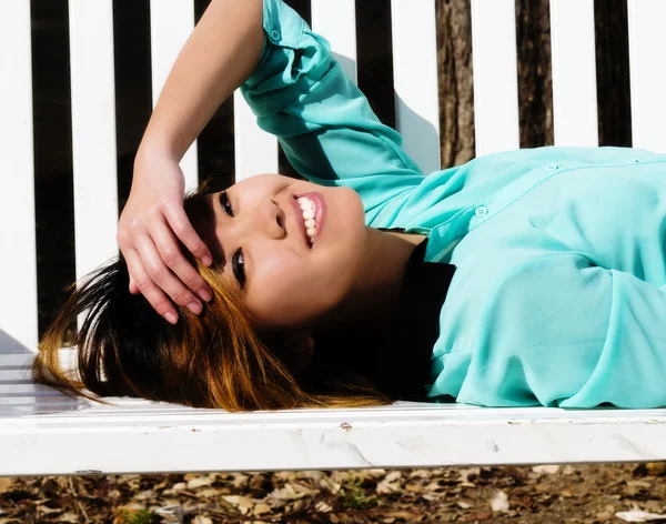 Sorrindo asiático americano mulher Reclinando no banco ao ar livre — Fotografia de Stock