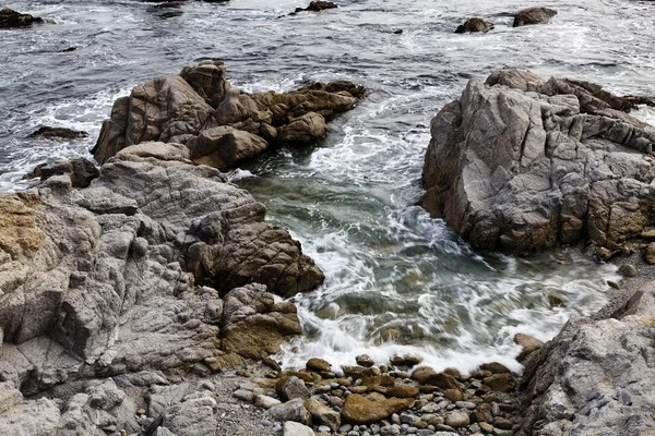 Water van de Oceaan op een rotsachtige strand stijgende — Stockfoto