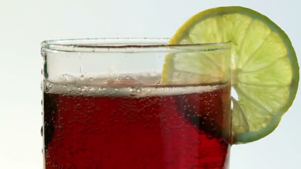 Bebida carbonatada vermelha derramada em limão de vidro — Vídeo de Stock